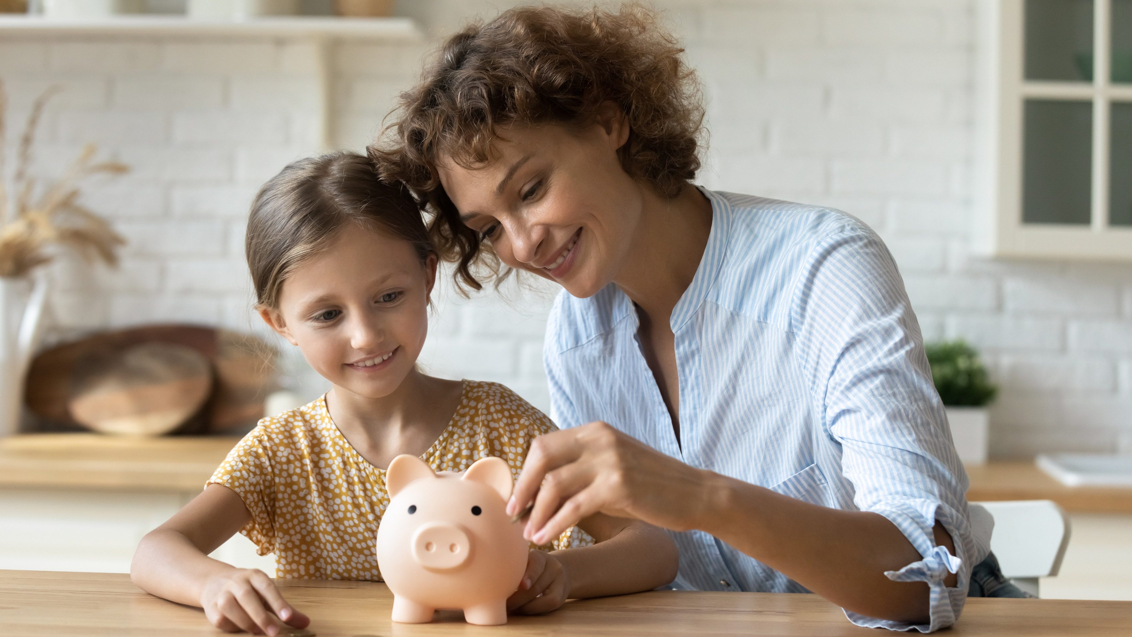 Setting good example. Young parent mother teach child little daughter girl to manage finances save money spend earnings with economy plan family budget. Friendly mom and kid thrift coins in piggybank