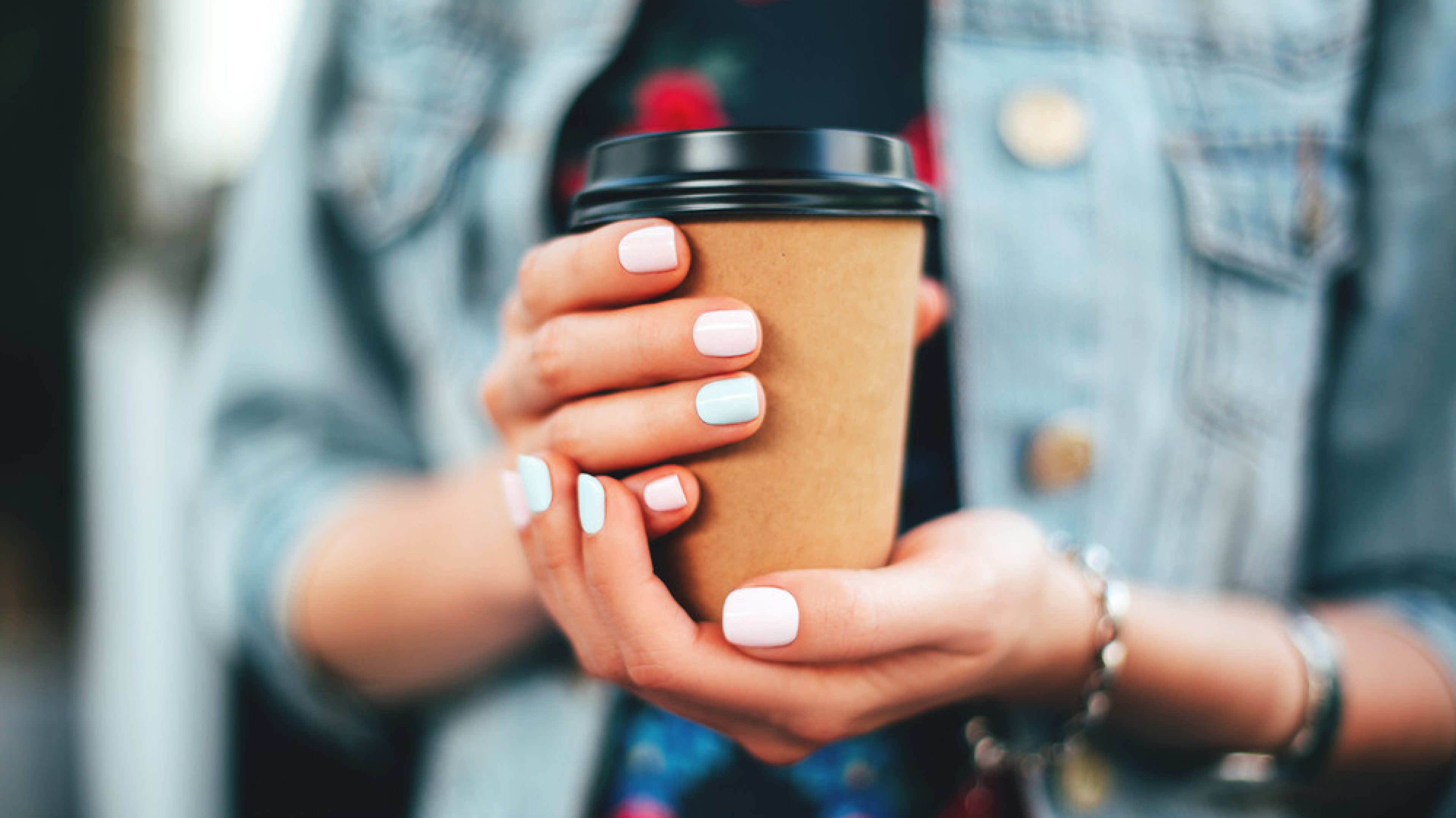 Female hand with paper cup of coffee take away.